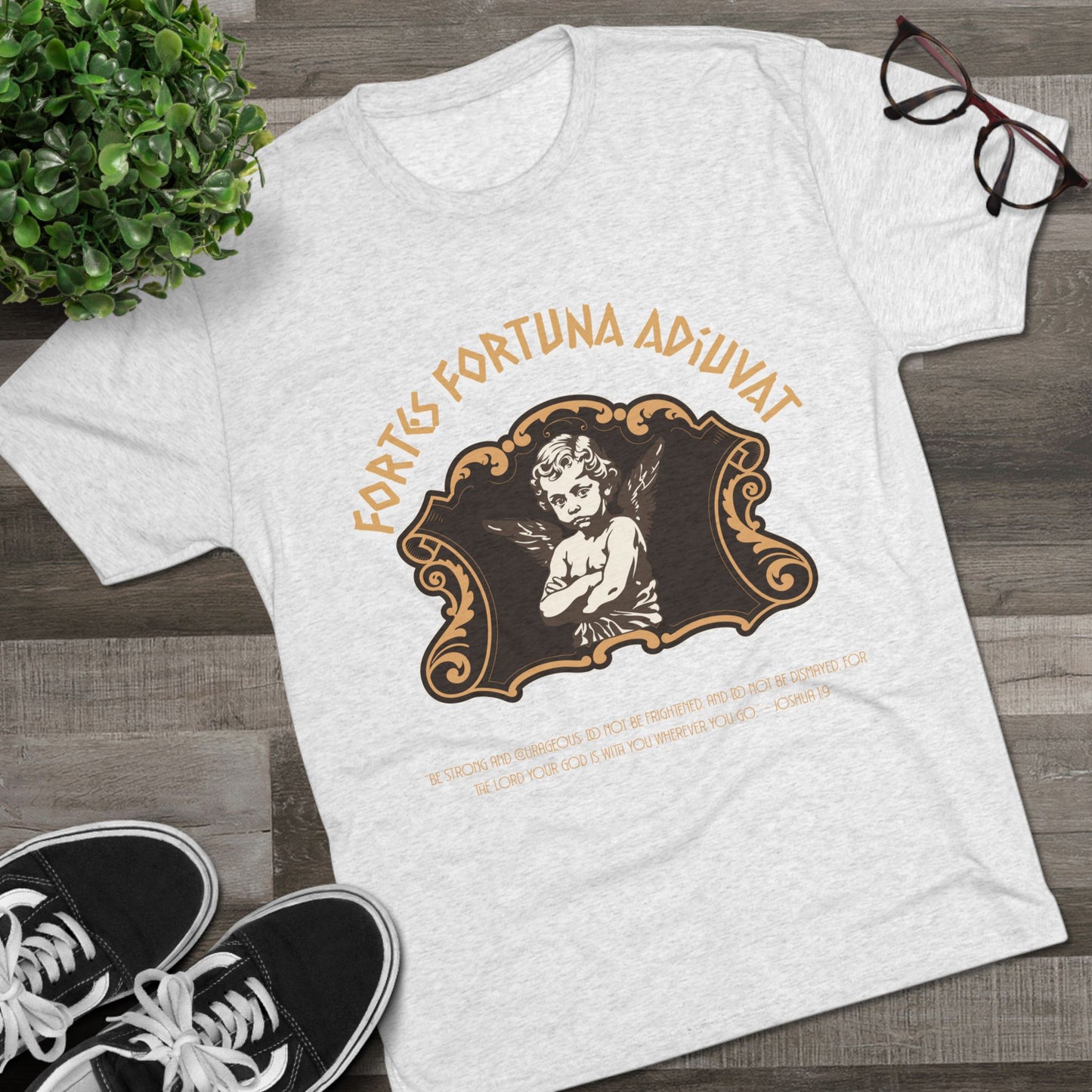 White t-shirt with vintage-style graphic and text on a wooden surface with shoes and glasses.